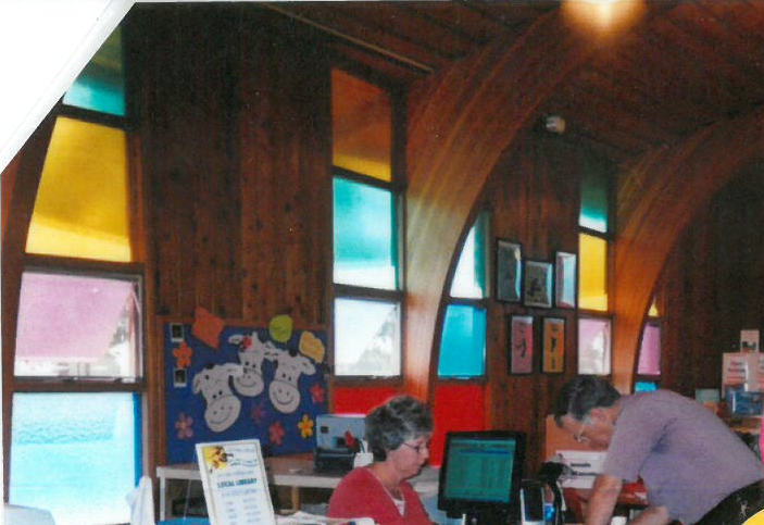 woman checking books out for man in the library