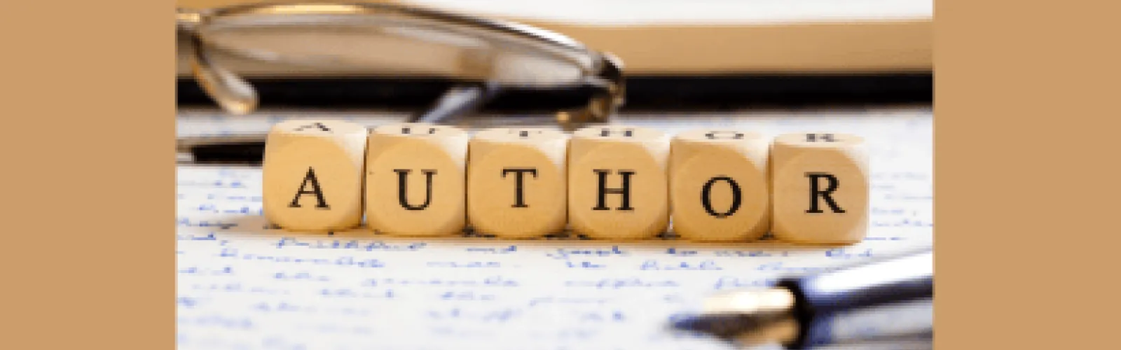 Author spelled out with blocks on a manuscript with glasses in the background