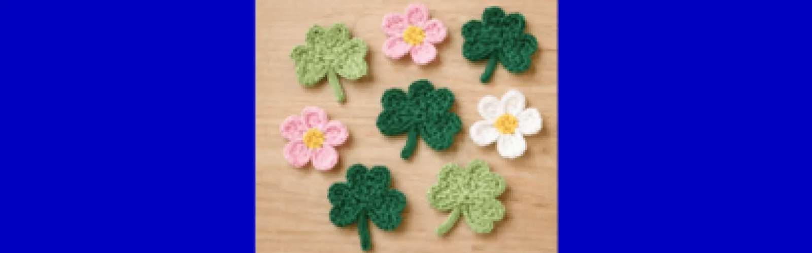 three dark green clovers two light green clovers two pink and one white crocheted flower.