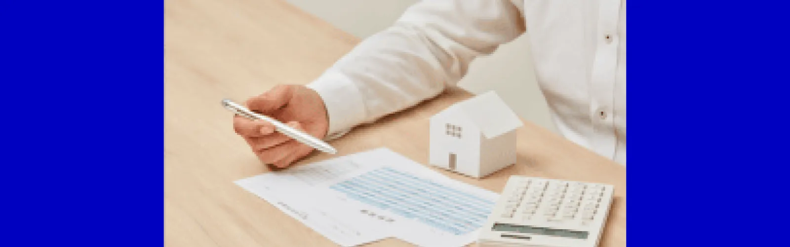 man looking at spreadsheet calculator house holding a pen