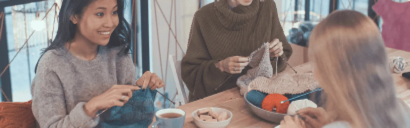 3 women sitting a a table with tea knitting