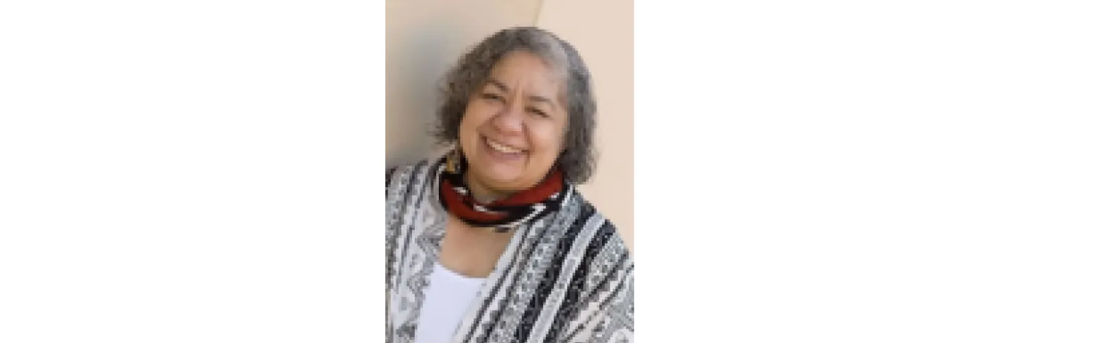 woman with chin length gray hair in a black and white shirt with a red black and white scarf