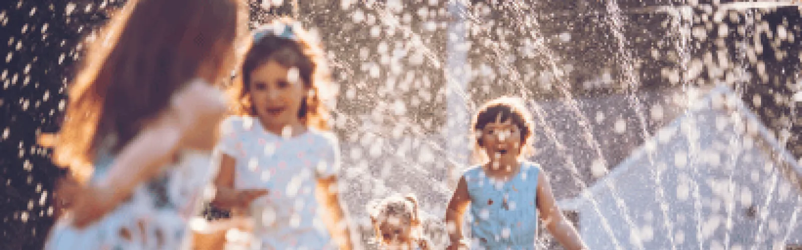 4 children playing in a sprinkler